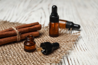 Photo of Bottles with cinnamon oil and sticks on wooden table