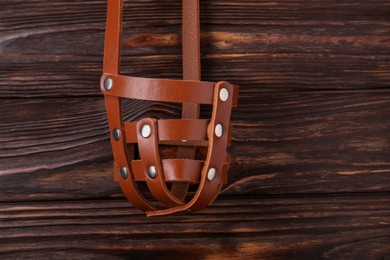 Photo of Brown leather dog muzzle on wooden table, top view