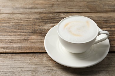 Tasty cappuccino in coffee cup on wooden table, closeup. Space for text
