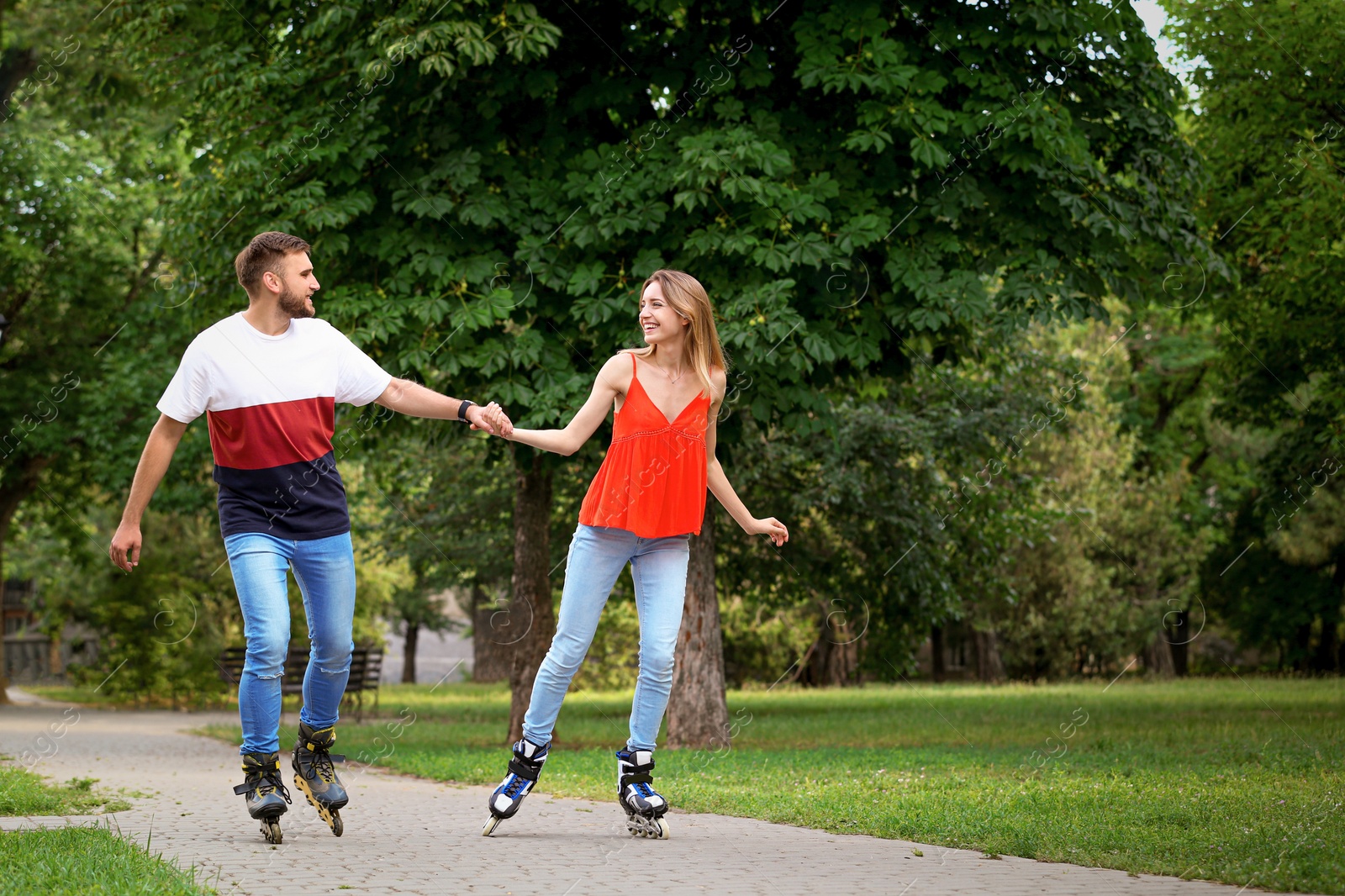 Photo of Young happy couple roller skating in summer park