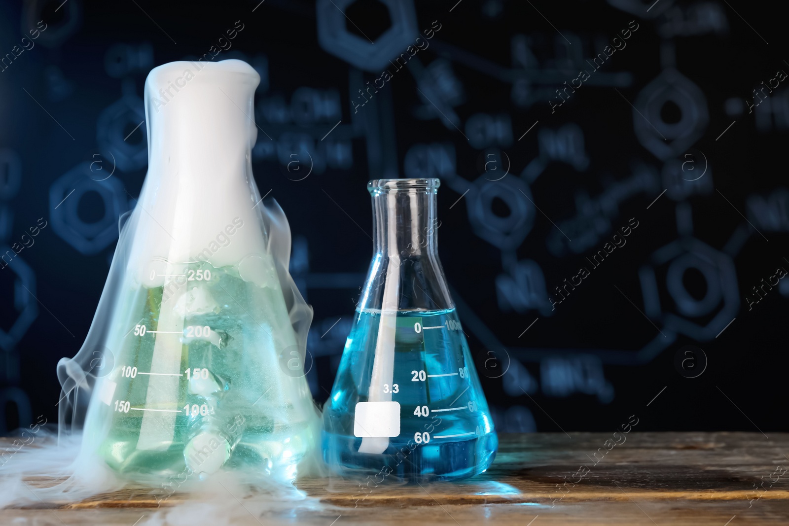 Photo of Laboratory glassware with colorful liquids and steam on wooden table against black background, space for text. Chemical reaction