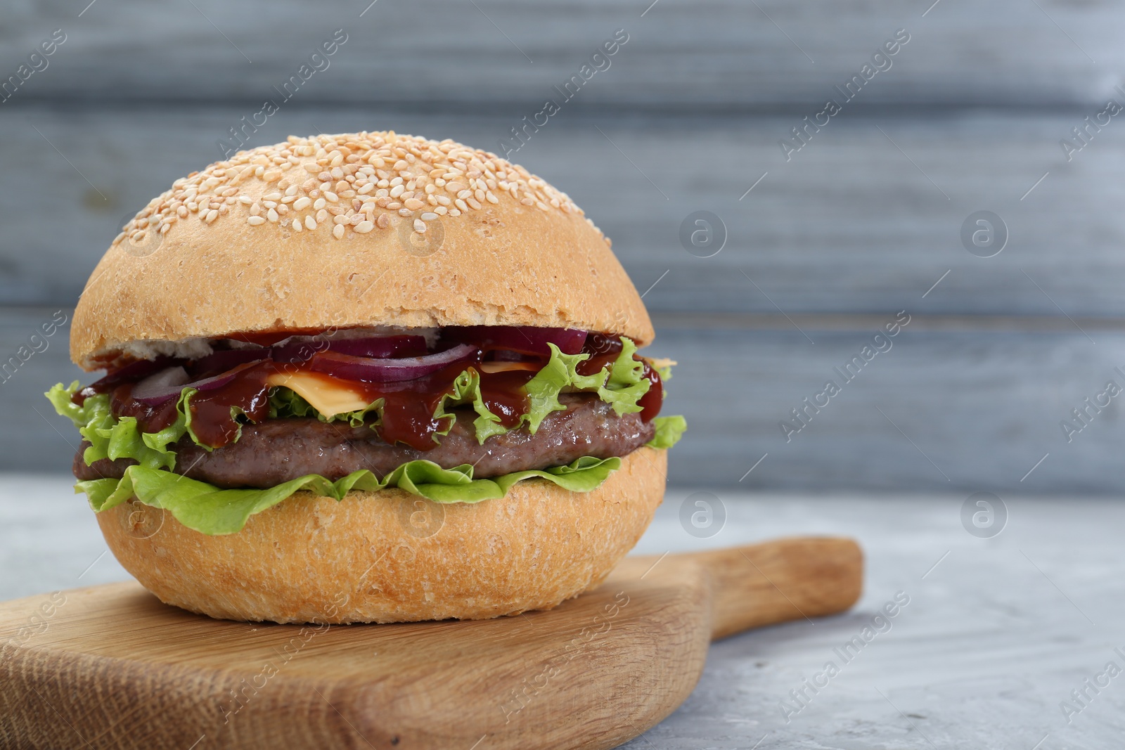 Photo of Delicious cheeseburger on grey table, closeup. Space for text