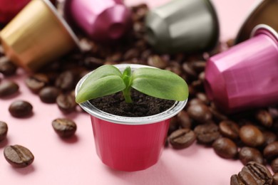 Photo of Coffee capsules, seedling and beans on pink background, closeup