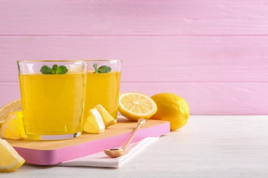 Glasses of lemon jelly served on light wooden table against color background. Space for text