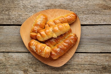 Delicious sausage rolls on wooden table, top view