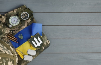 Photo of MYKOLAIV, UKRAINE - SEPTEMBER 26, 2020: Tactical gear, military uniform and Ukrainian flag on grey table, flat lay. Space for text