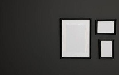 Photo of Empty frames on black wall. Mockup for design