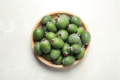 Fresh green feijoa fruits in bowl on light table, top view