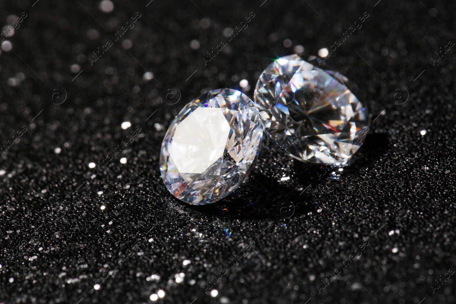 Photo of Two beautiful diamonds on dark shiny background, closeup