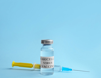 Photo of Chickenpox vaccine and syringe on light blue background. Varicella virus prevention