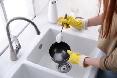 Photo of Woman using baking soda to clean pot, closeup