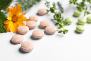 Photo of Different pills, herbs and flower on white background, closeup with space for text. Dietary supplements