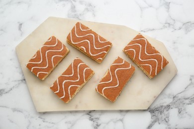 Tasty sponge cakes on white marble table, top view