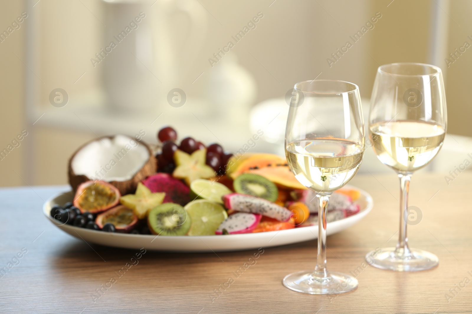 Photo of Delicious exotic fruits and wine on wooden table