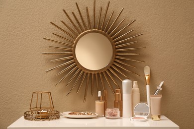 Photo of Stylish round mirror on wall over dressing table with makeup products