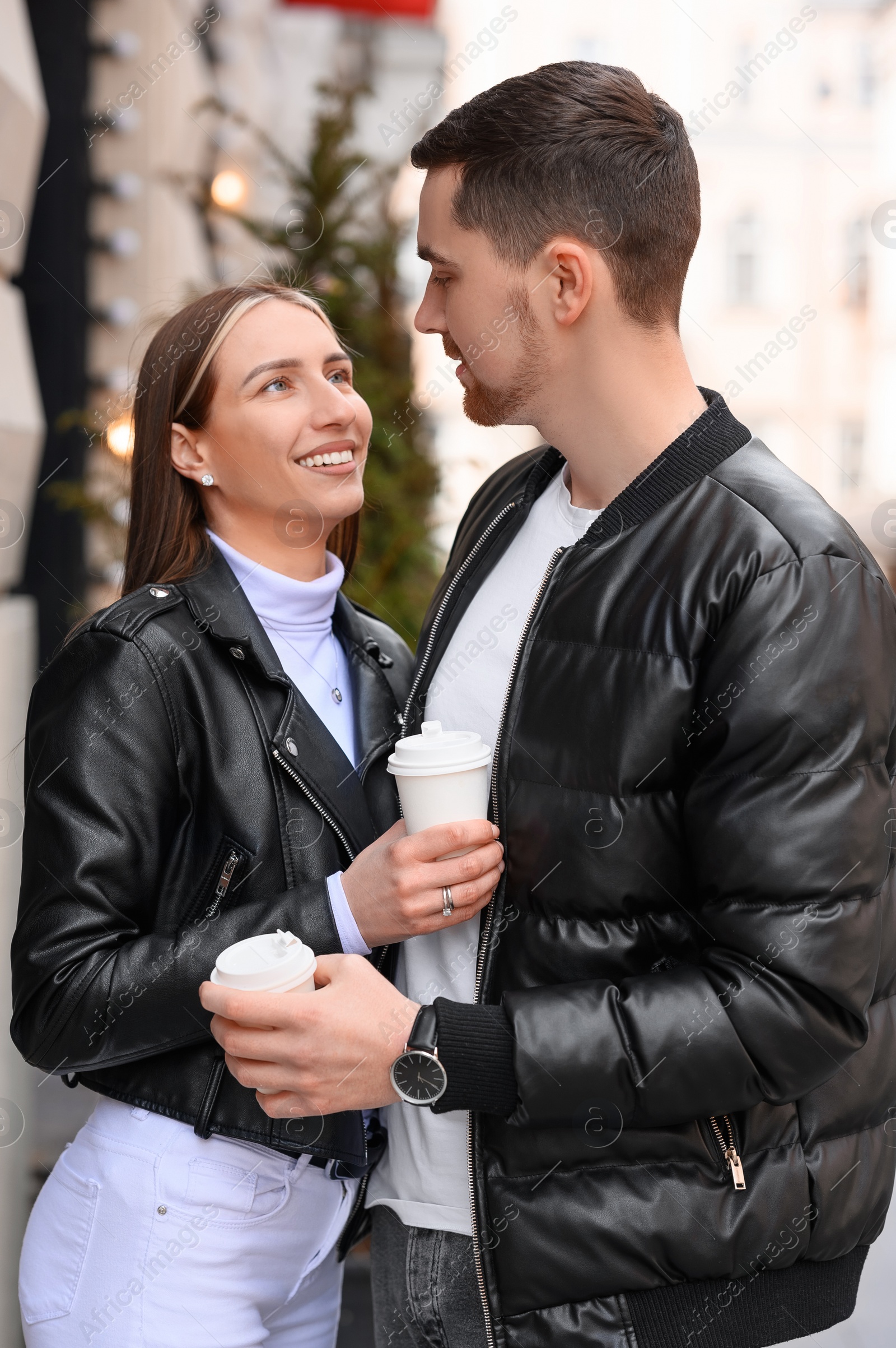 Photo of Lovely young couple with cups of coffee enjoying time together outdoors. Romantic date