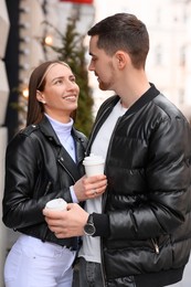 Photo of Lovely young couple with cups of coffee enjoying time together outdoors. Romantic date