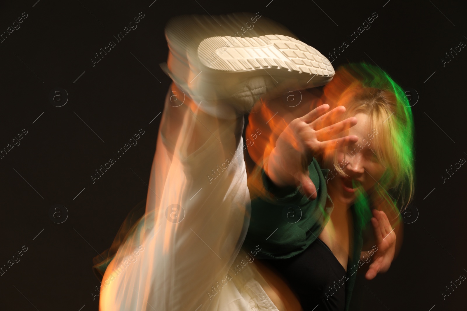 Photo of Young woman performing contemporary dance on black background, motion blur effect