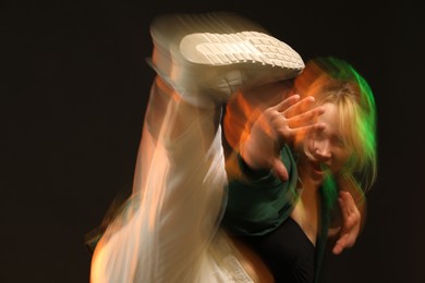 Photo of Young woman performing contemporary dance on black background, motion blur effect