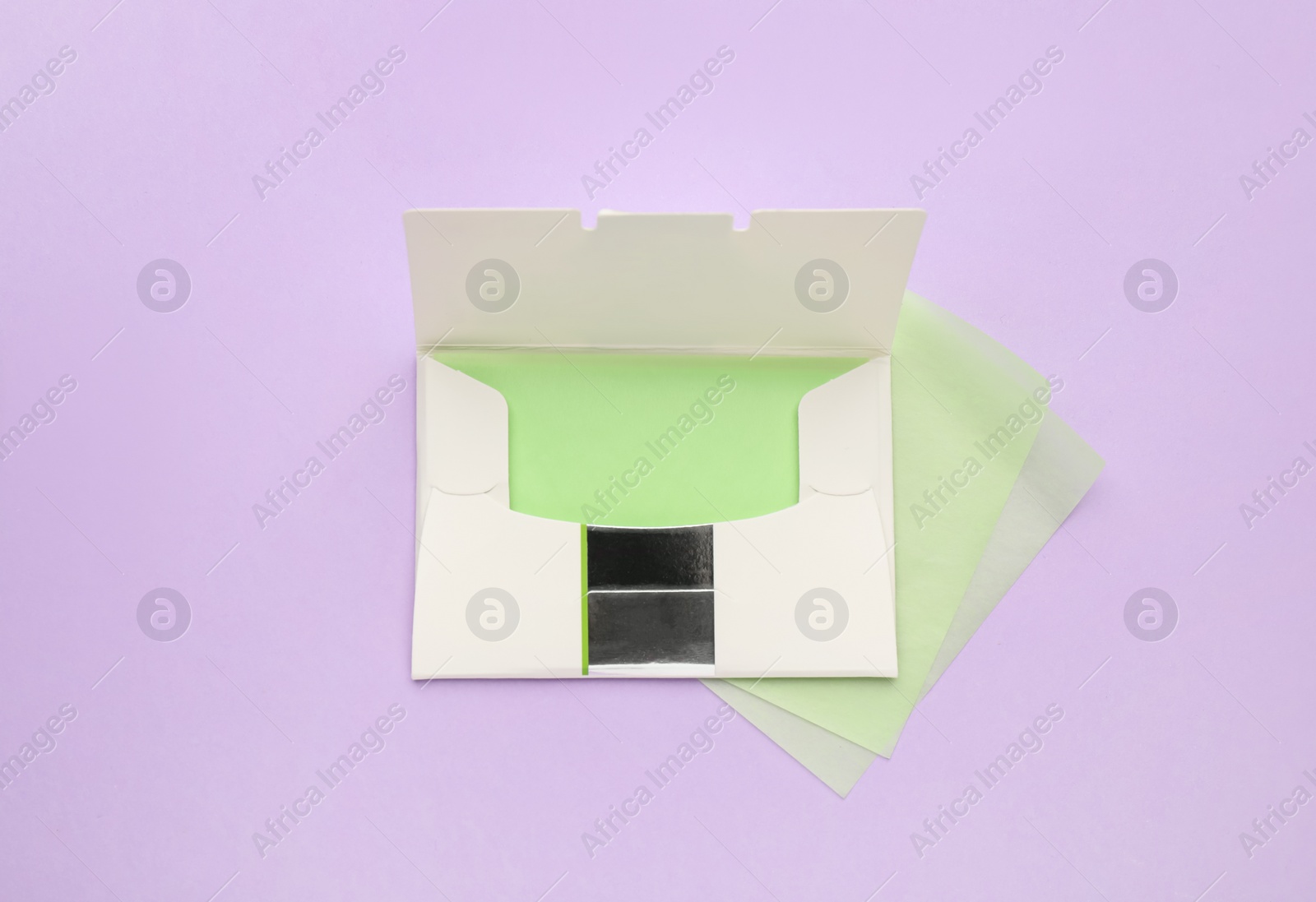 Photo of Package with facial oil blotting tissues on violet background, flat lay. Mattifying wipes