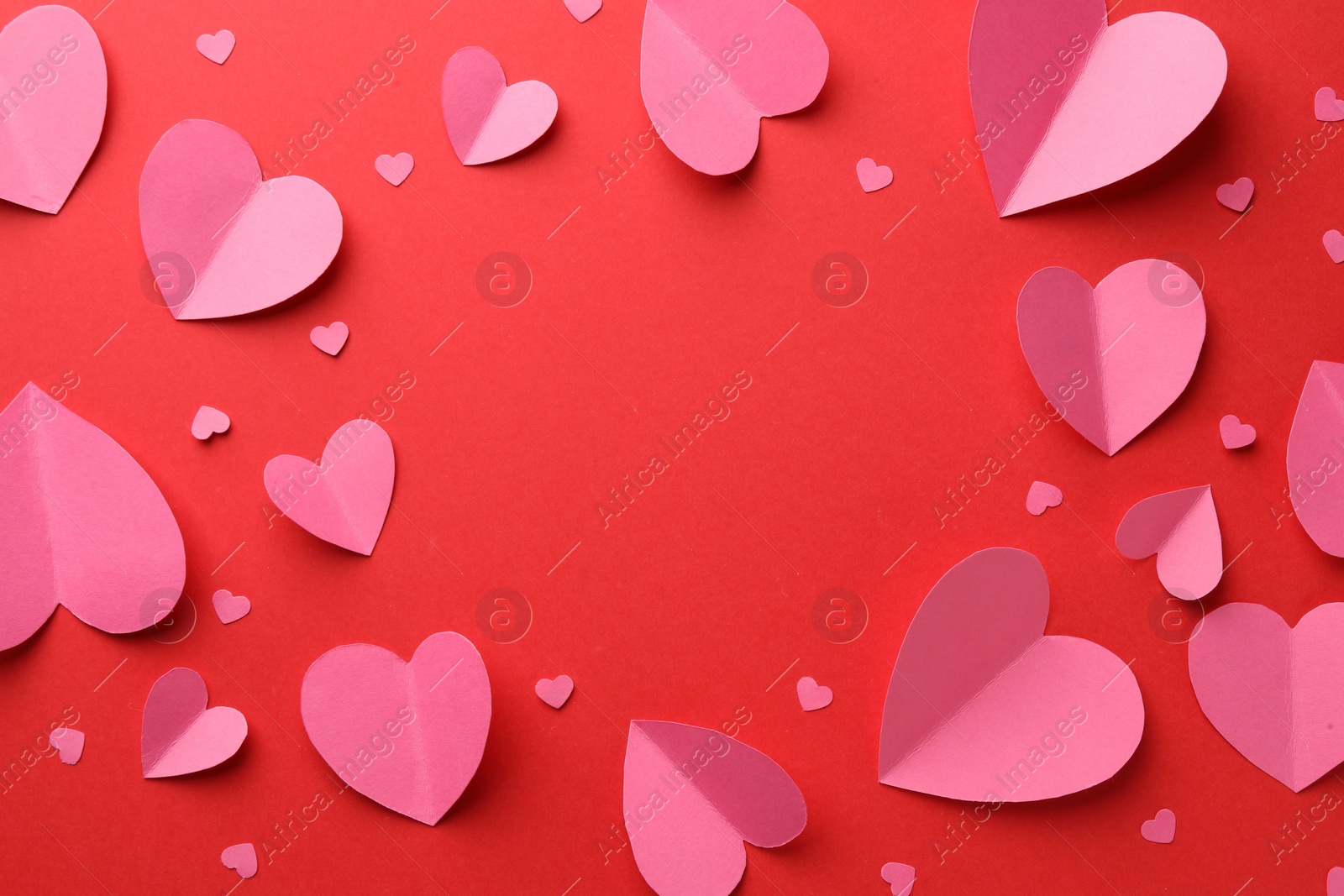 Photo of Frame of pink paper hearts on red background, flat lay. Space for text