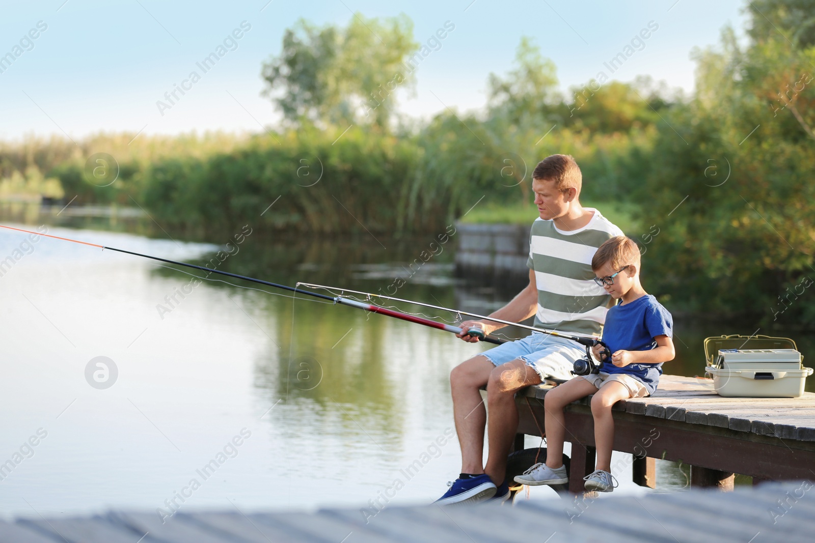 Photo of Dad and son fishing together on sunny day