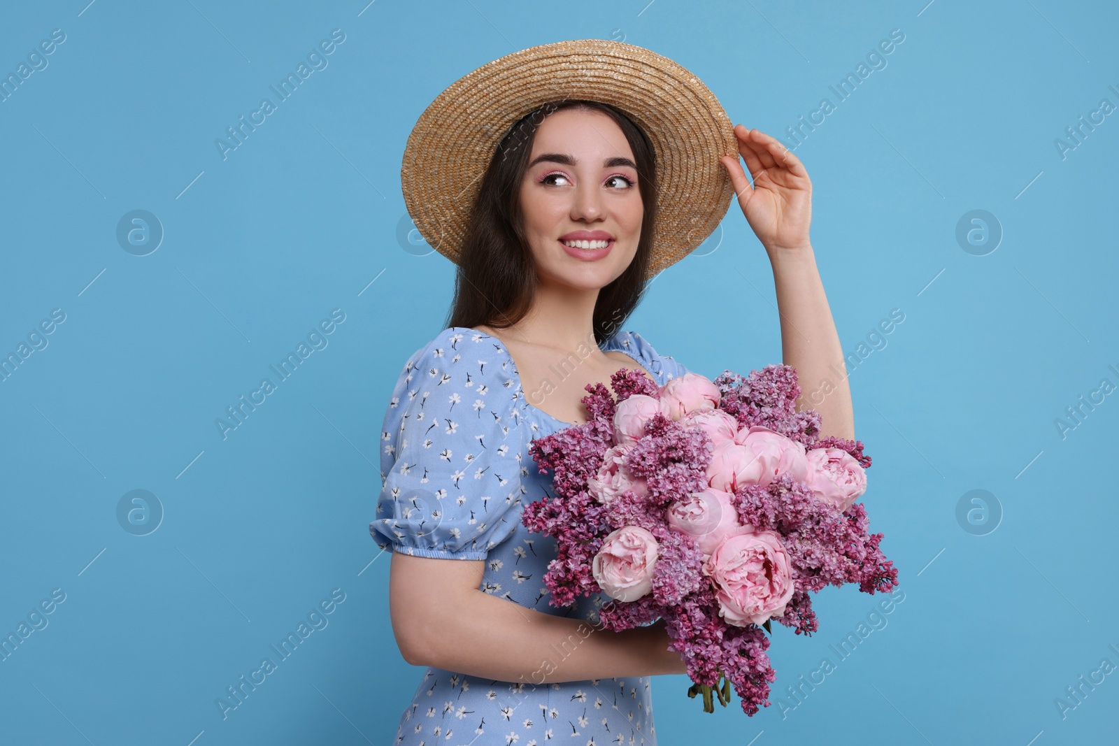 Photo of Beautiful woman with bouquet of spring flowers on light blue background