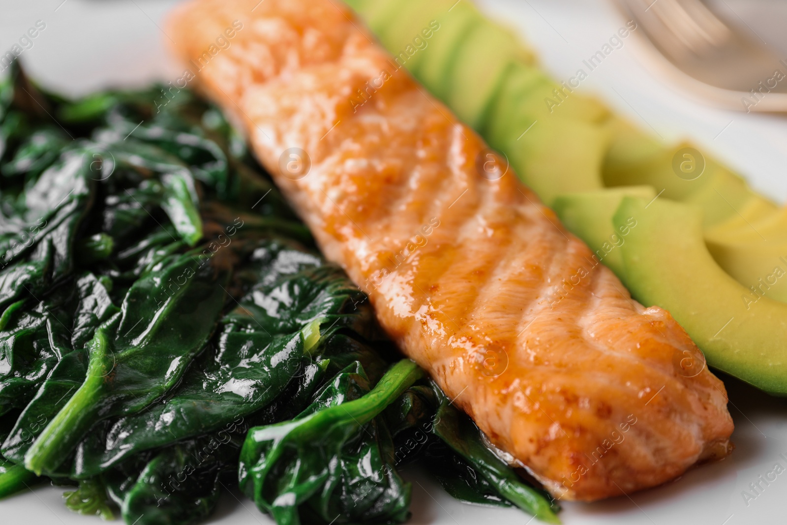 Photo of Tasty salmon with spinach and avocado on plate, closeup