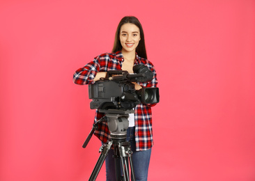 Operator with professional video camera on pink background