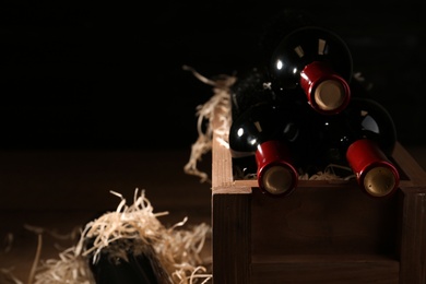 Photo of Wooden crate with bottles of wine on dark background