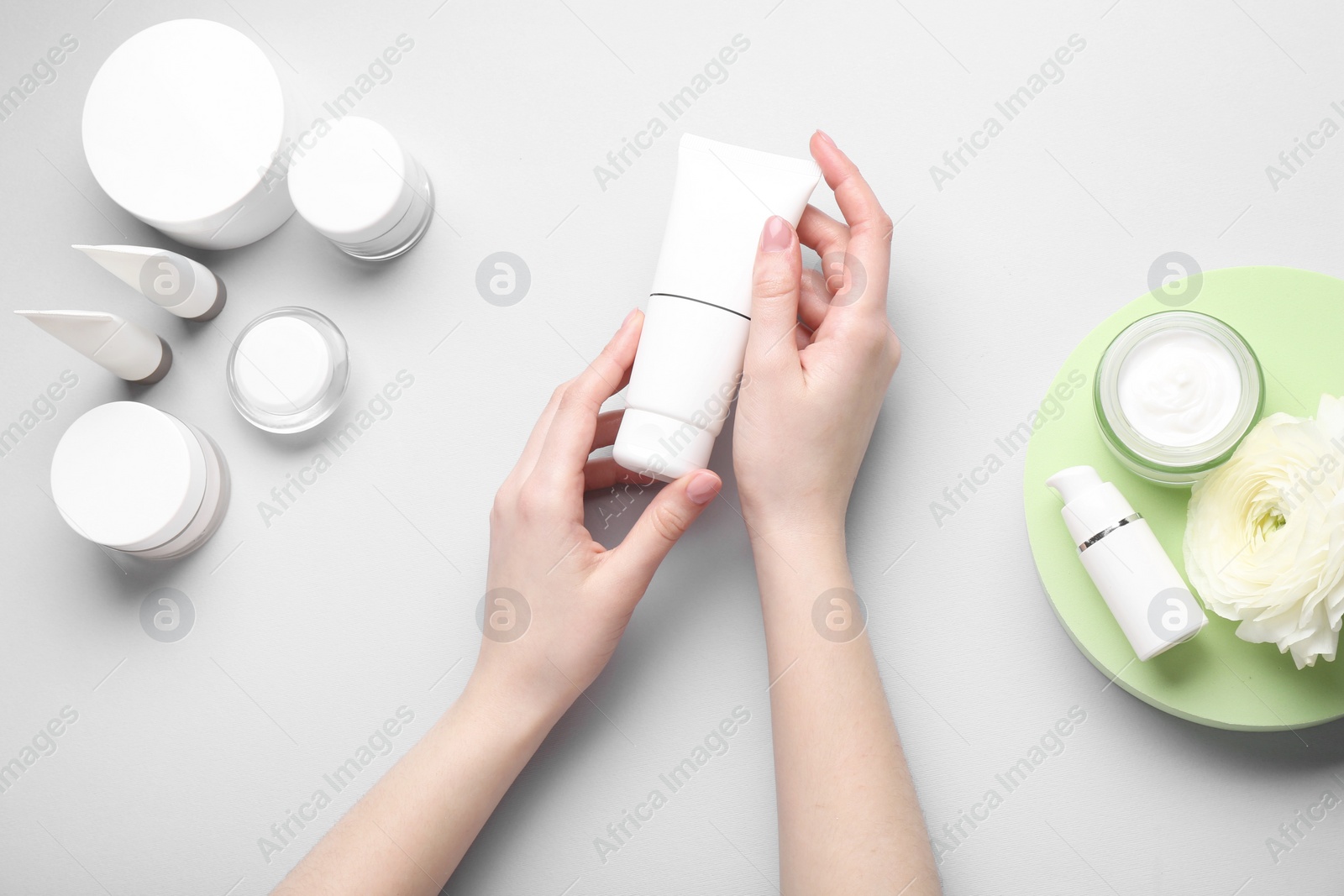 Photo of Woman holding tube of cream on light background, top view