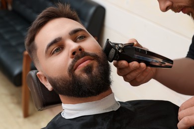 Professional hairdresser working with client in barbershop, closeup