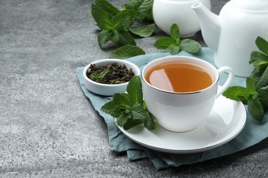 Cup of hot aromatic mint tea on grey table. Space for text
