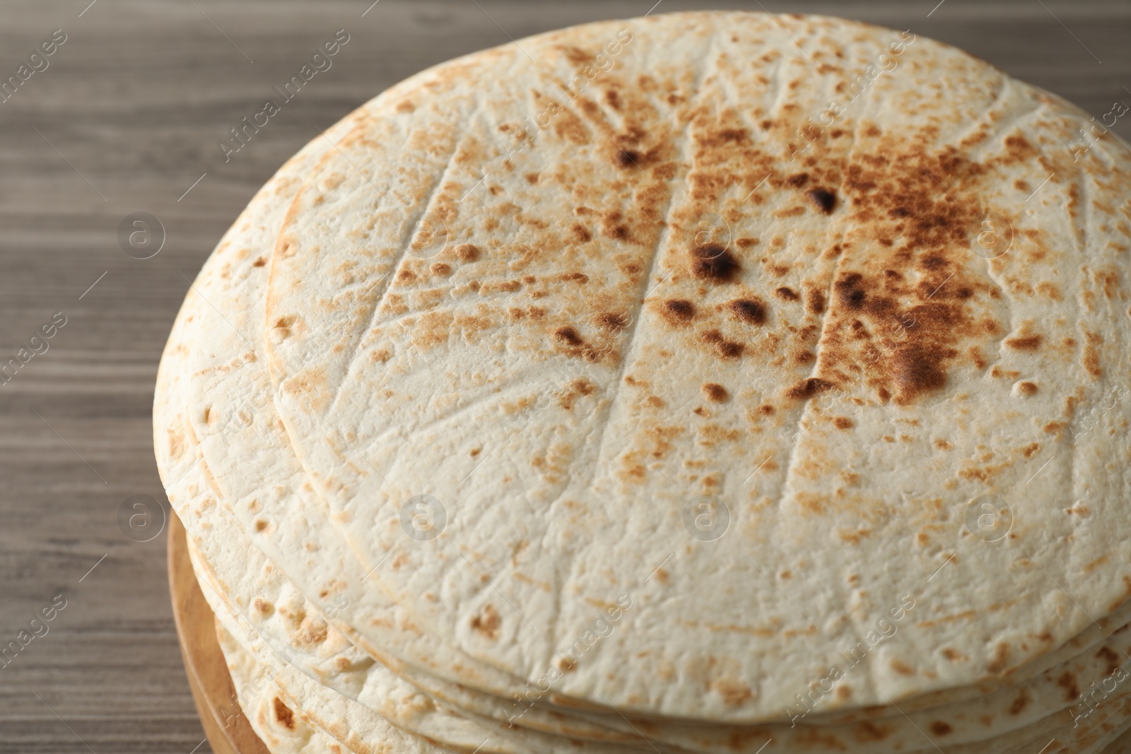 Photo of Many tasty homemade tortillas on wooden table, closeup