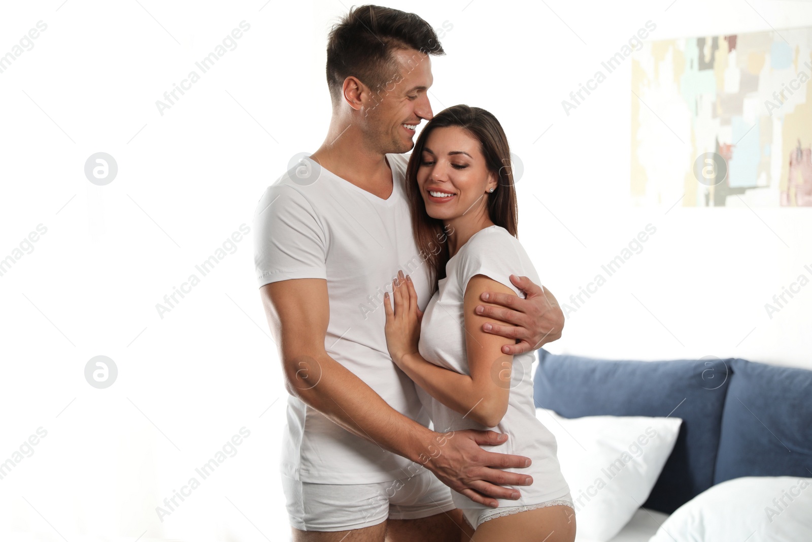 Photo of Happy couple wearing underwear in modern bedroom