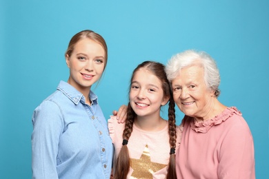 Photo of Happy sisters with their grandmother on light blue background
