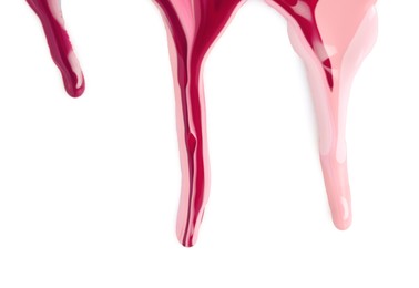 Spilled different nail polishes on white background, top view