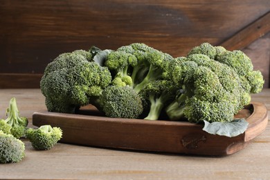 Photo of Tray with fresh raw broccoli on wooden table, closeup