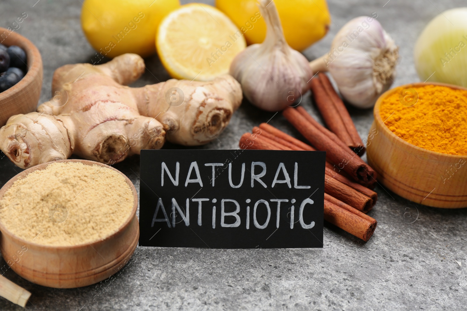 Photo of Different fresh products and card with phrase Natural Antibiotic on grey table, closeup