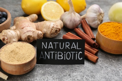 Different fresh products and card with phrase Natural Antibiotic on grey table, closeup