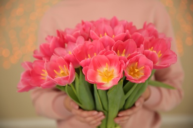 Girl with spring tulips on blurred background, closeup. International Women's Day