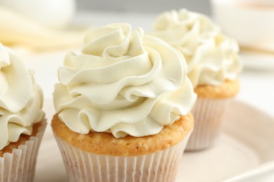 Tasty cupcakes with vanilla cream on table, closeup