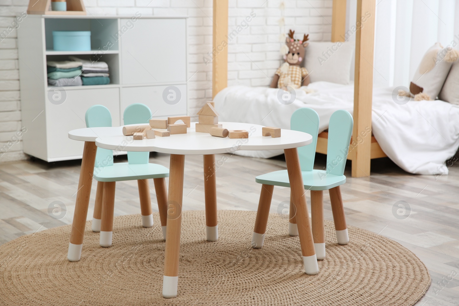 Photo of Little table and chairs with bunny ears in baby room. Interior design