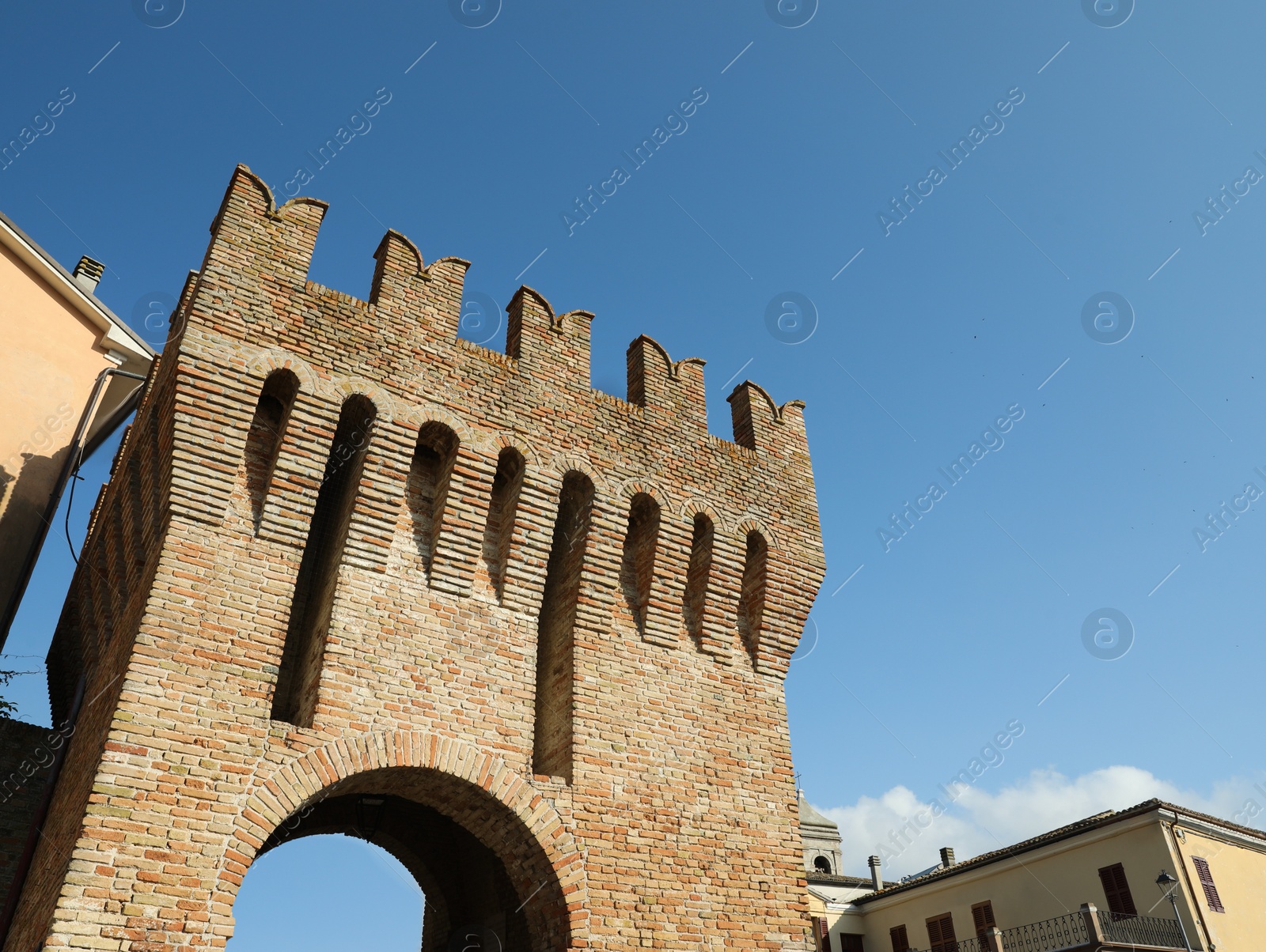 Photo of Brick city tower against blue sky on sunny day, low angle view