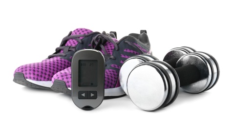 Photo of Digital glucometer, dumbbells and sneakers on white background. Diabetes concept