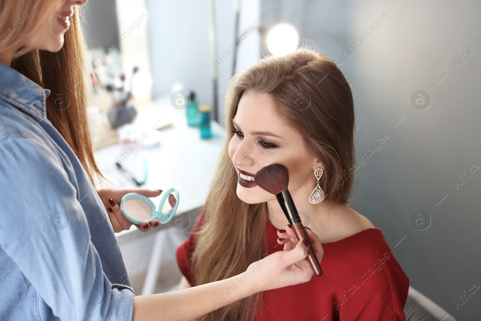 Photo of Professional makeup artist working with beautiful young woman in studio