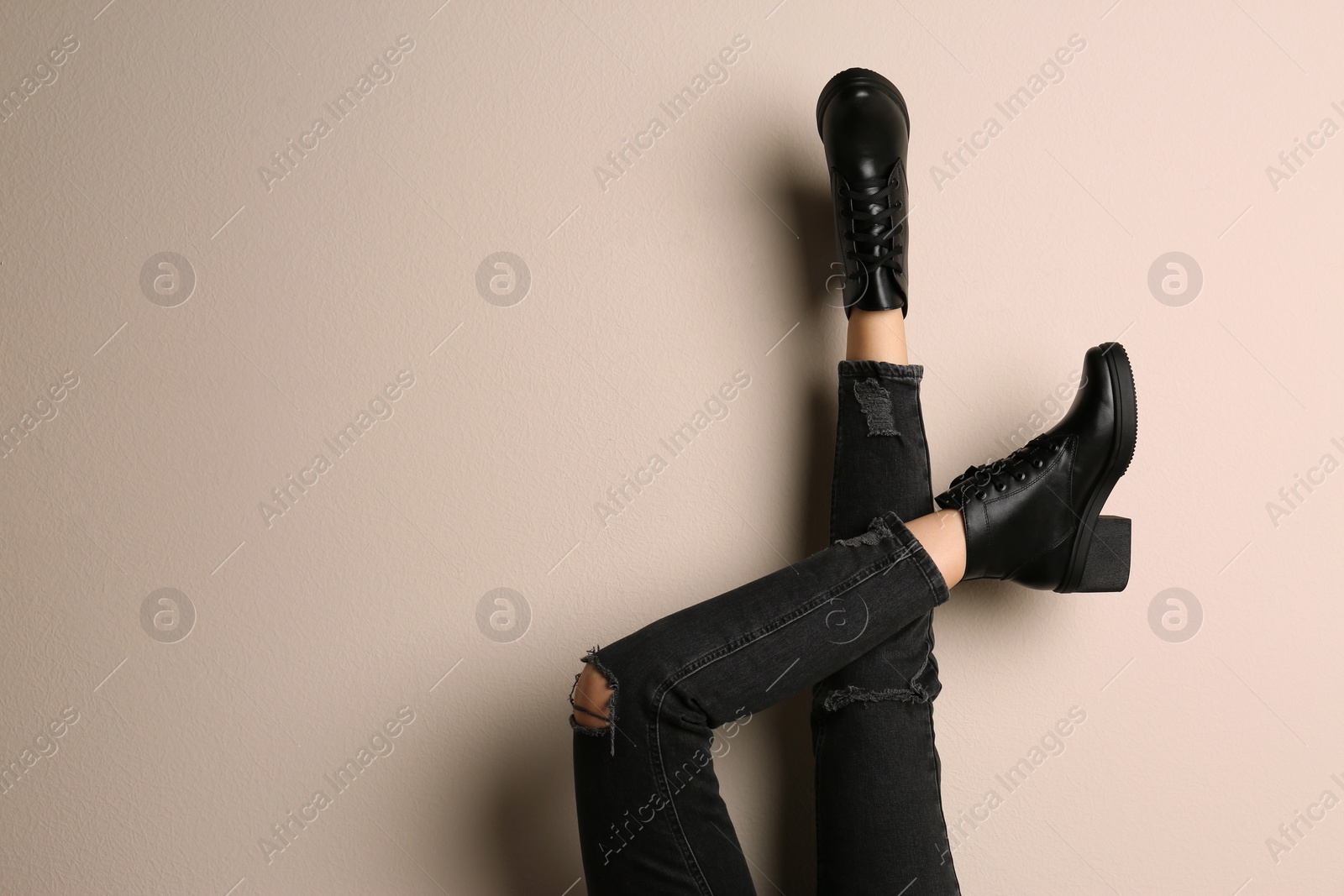Photo of Woman wearing stylish boots on beige background, closeup. Space for text