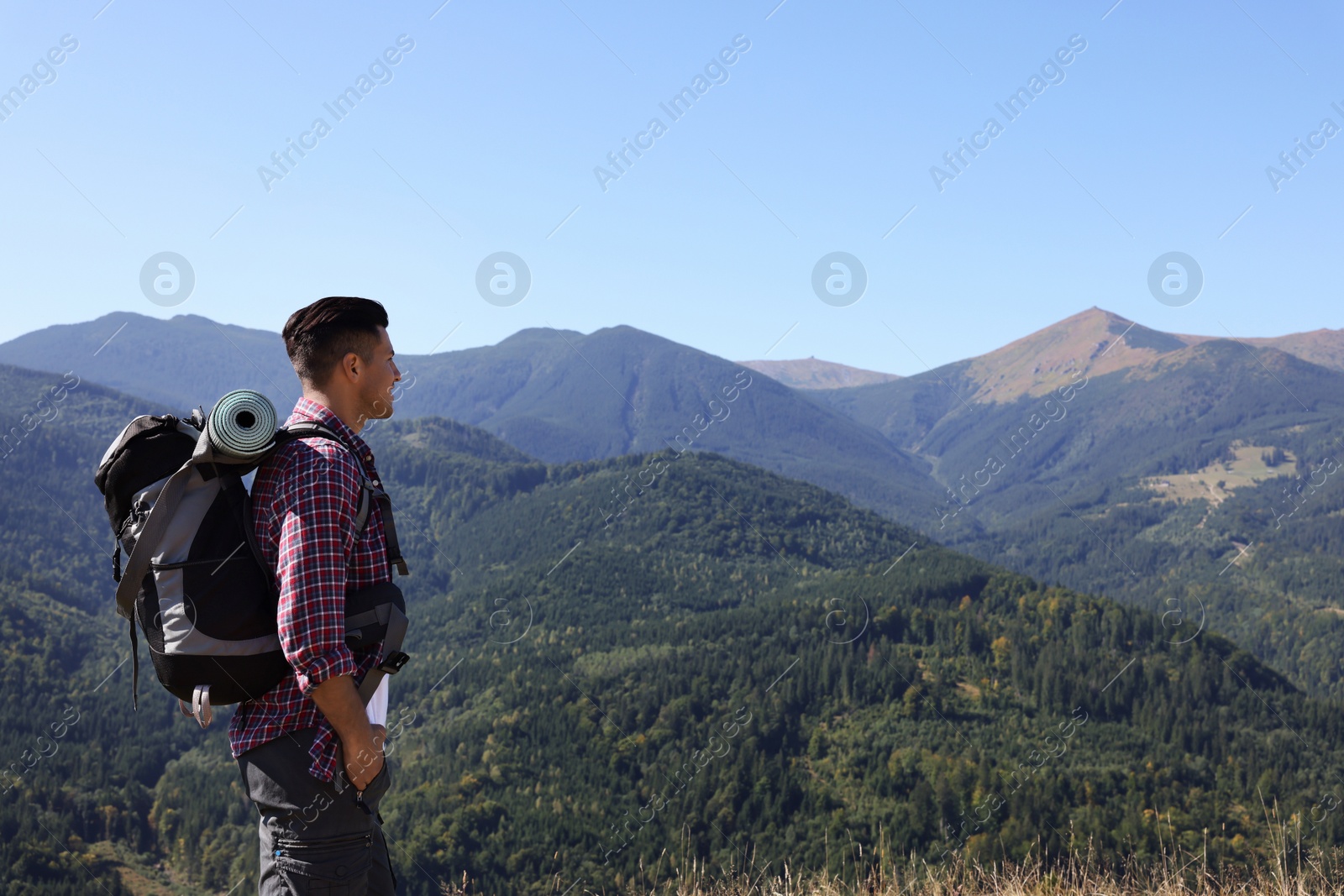 Photo of Tourist with backpack enjoying view in mountains on sunny day