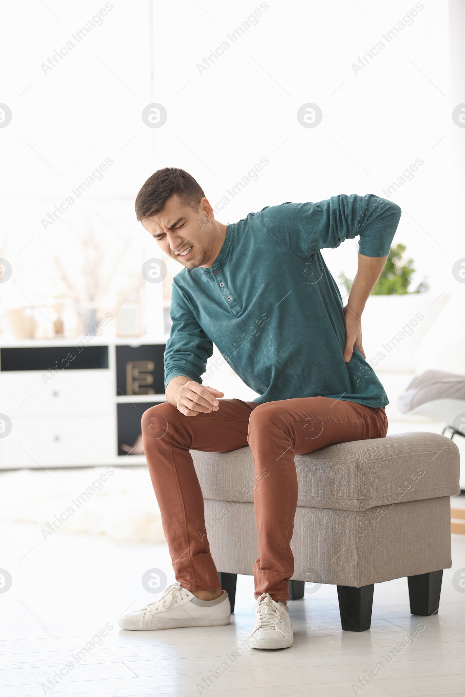 Photo of Young man suffering from back pain at home