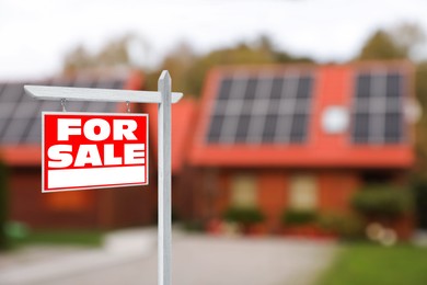 Sale sign near beautiful house outdoors. Red signboard with words